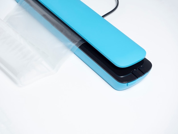 Primo piano di un confezionatore sottovuoto blu isolato su uno sfondo blu brillante il pacchetto è inserito i