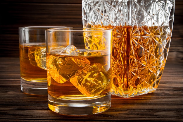 Closeup of bottle and two glasses with ice and whiskey