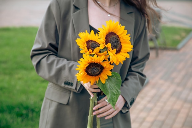 背景をぼかした写真に女性の手でひまわりの花束をクローズ アップ