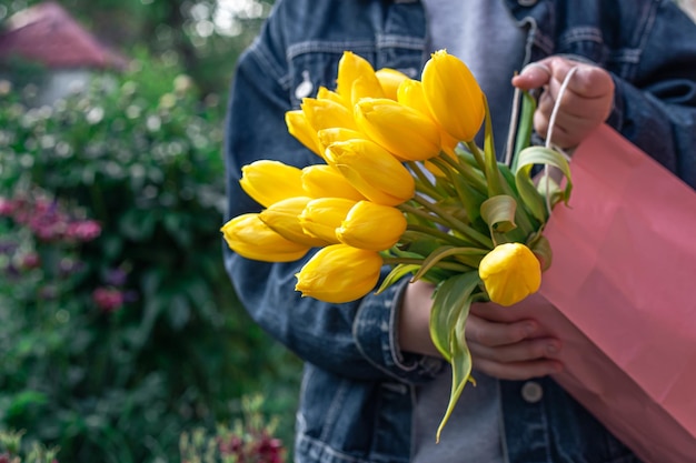 Primo piano un mazzo di tulipani gialli nelle mani di una bambina