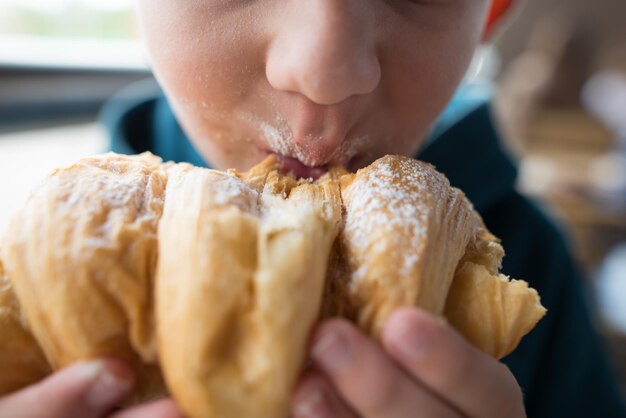 Closeup of a boy eating a croissant Cropped photo