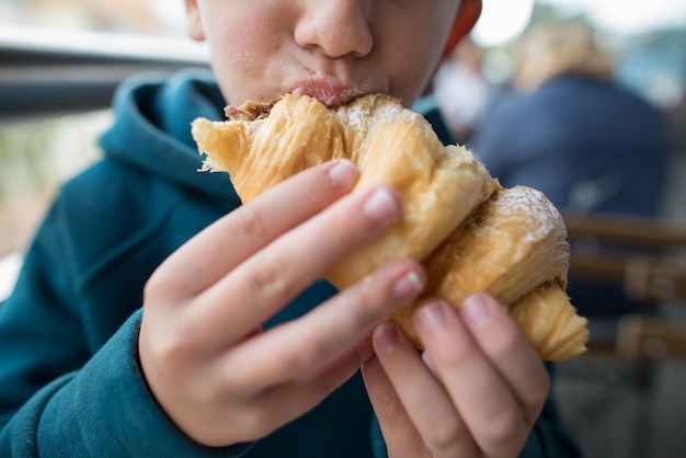 Closeup of a boy eating a croissant Cropped photo