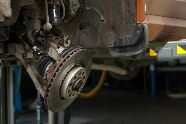 A closeup on the brake system of a car with pads discs a caliper on a lift in a vehicle repair workshop auto service industry