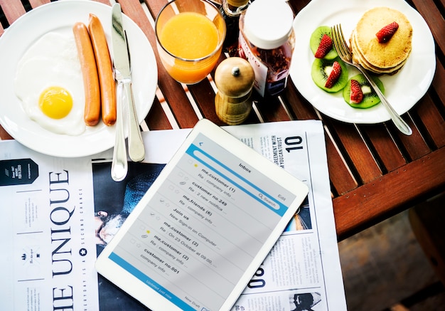 Photo closeup of breakfast with digital tablet and newspaper