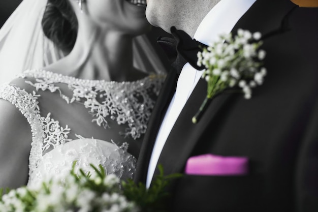 Closeup of a bride and groom smiling with a focus on the groom39s tie and the bride39s bouquet