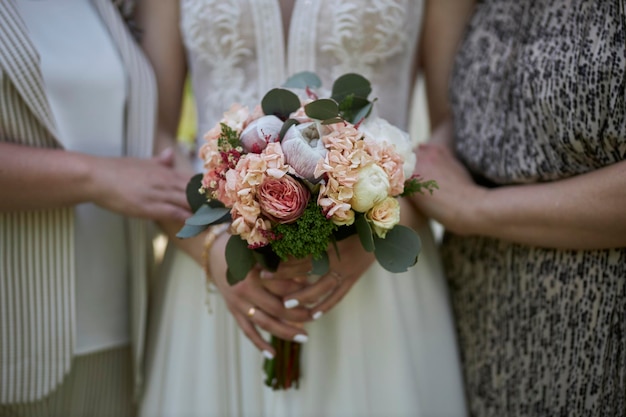 Closeup of a bride with a bouquet in her hands and with her mother and grandmother