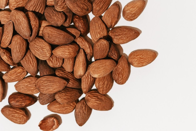 Closeup of brown almond nuts on a white isolated background Image for your design