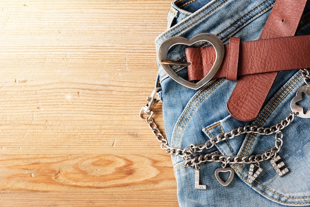 Closeup brown leather woman belt with metal heart shaped belt buckle and LOVE wallet chain