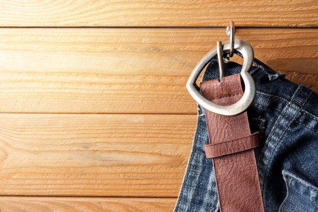 Closeup brown leather woman belt with metal heart shaped belt buckle on wooden board