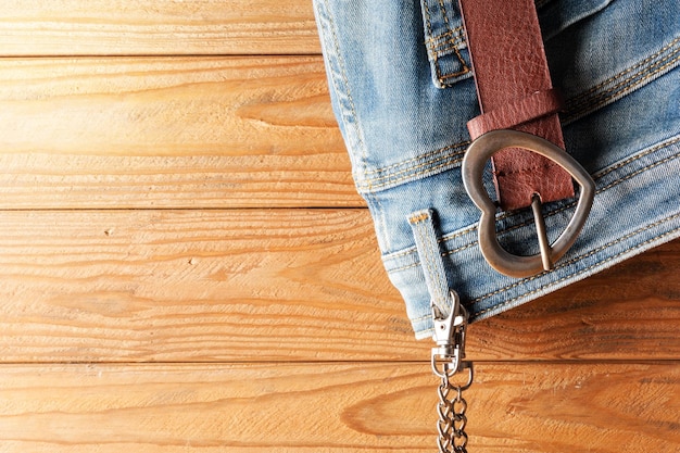 Closeup brown leather woman belt with metal heart shaped belt buckle on wooden board