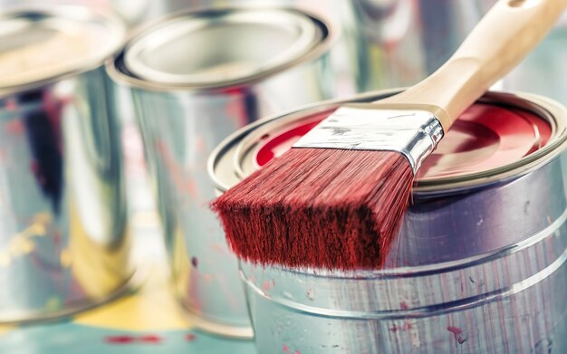 Foto pennello di primo piano con colore rosso disteso su una lattina di vernice