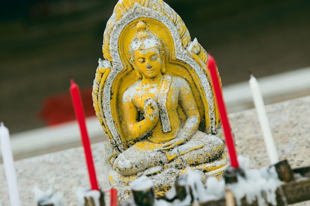 Primo piano delle candele buddiste dell'altare e della statua del buddha in preghiera