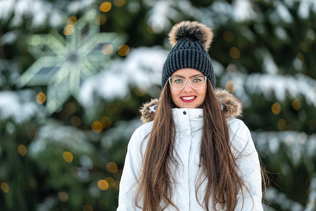 Closeup buiten portret van jonge vrouw in brillen over kerstboom lichten achtergrond