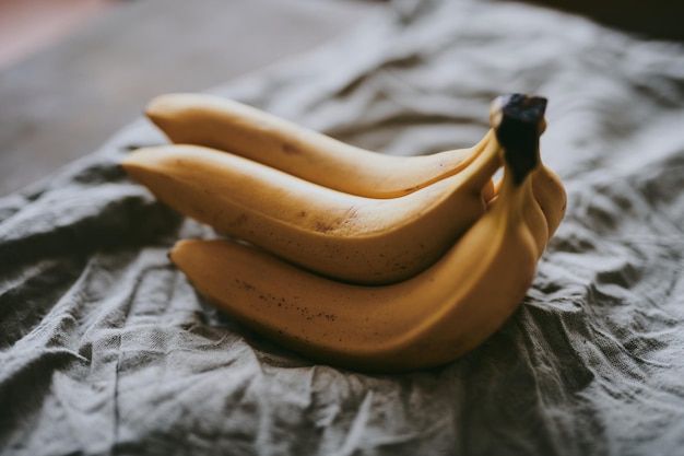 Крупным планом связка бананов на фоне темной ткани
