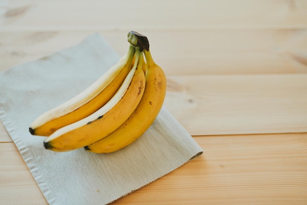 Foto closeup di un mucchio di banane su uno sfondo di tavolo da cucina in legno