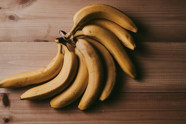 Foto closeup di un mucchio di banane su uno sfondo di tavolo da cucina in legno