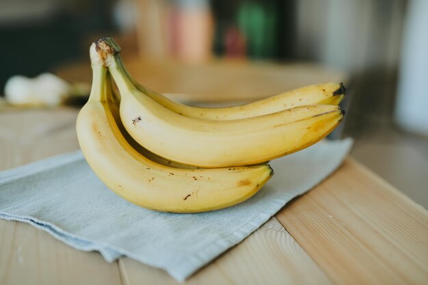 Крупным планом связка бананов на фоне деревянного кухонного стола