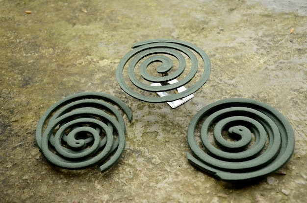 Photo closeup the bunch green mosquito coil with metal stand over out of focus brown background.