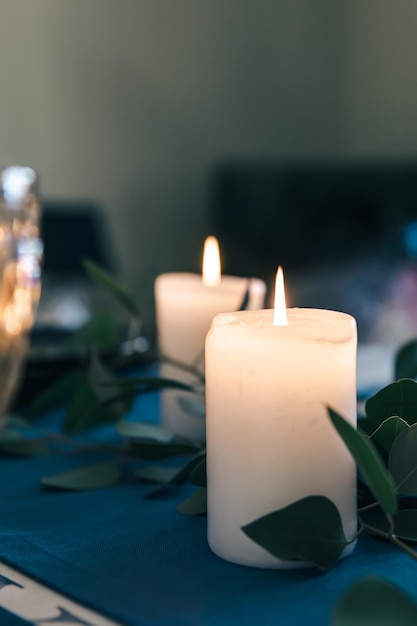 Photo closeup burning candles on the table among the leaves