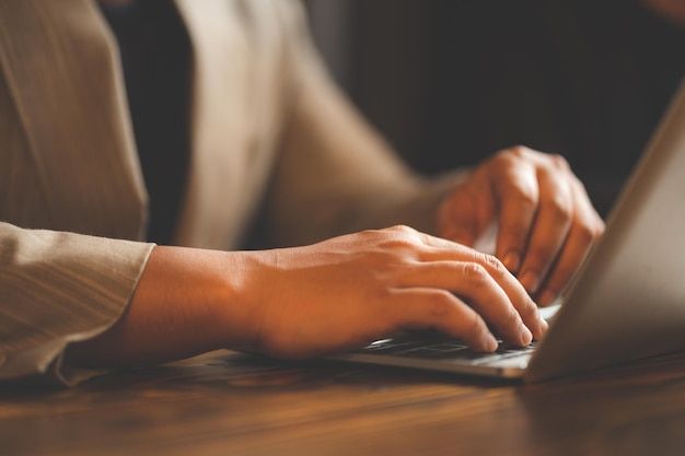 Mano d'affari del primo piano che lavora alla digitazione della tastiera del computer portatile del computer nell'ufficio moderno o dell'uomo d'affari del tavolo della scrivania del posto di lavoro di casa utilizzando il notebook per il lavoro di comunicazione della tecnologia online utilizzando il cyberspazio