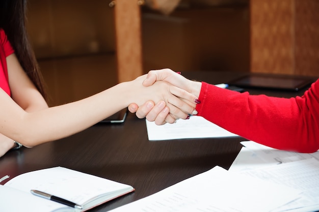 Closeup of a business handshake on the background of the table with papers