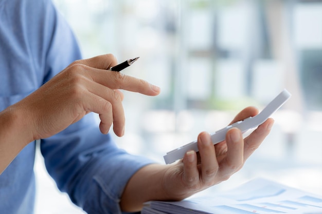 Closeup of a business man using a white calculator a financial businessman examining the numerical data on a company financial document he uses a calculator to verify the accuracy of numbers