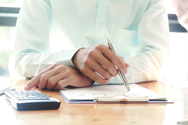 Closeup of business man writing on paper at desk