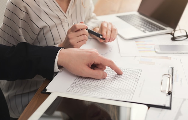 Closeup of business partners hands using tablet and laptop and checking documents. Financial background, count and pay an account, copy space