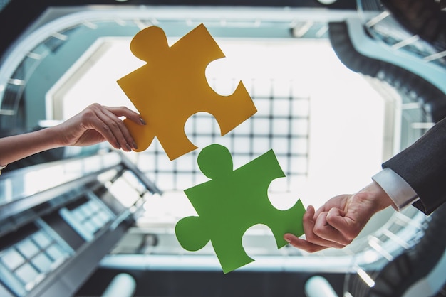 Photo closeup of business people wanting to put two pieces of puzzle together