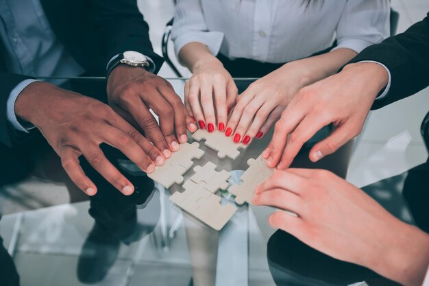 Foto squadra di affari del primo piano con i pezzi di un puzzle dietro una scrivania