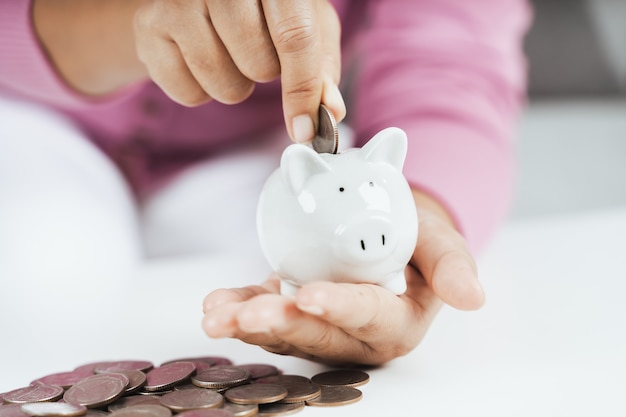 Closeup of business woman hand putting money coin into piggy bank for saving money. saving money and financial concept