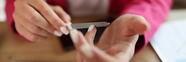 Foto primo piano della donna d'affari in giacca rosa seduta sul posto di lavoro e contando qualcosa sulle dita