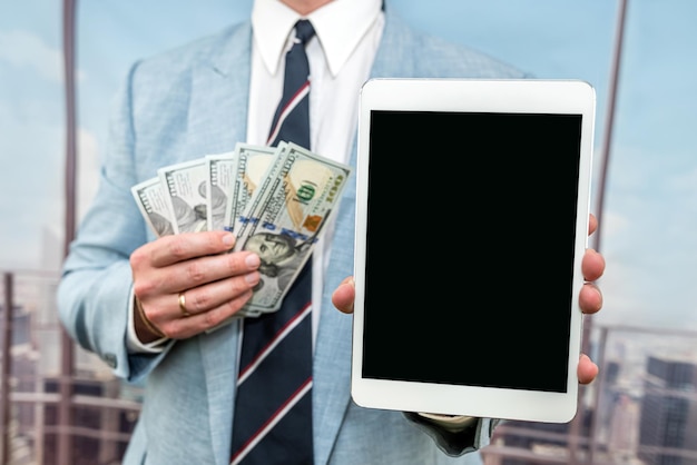 Closeup businessman in blue suit holding dollar bills and smartphone with blank black screen