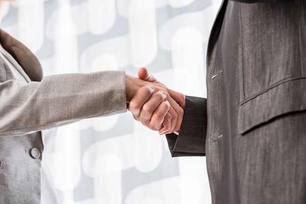 Photo closeup of businessman and businesswoman shaking hands in agreement