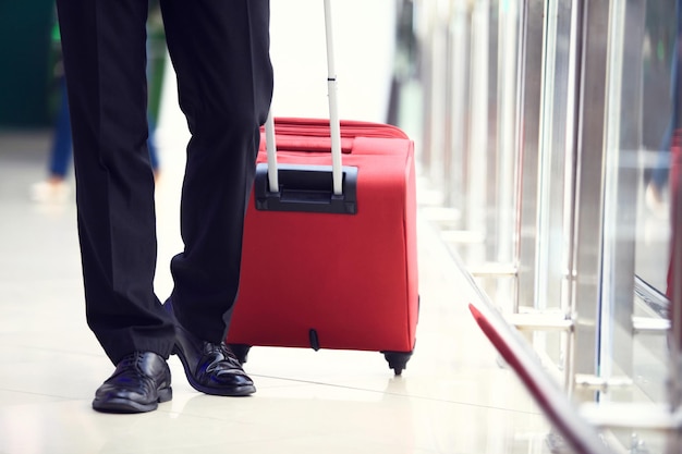 Photo closeup of businessman carrying suitcase while walking through a passenger boarding bridge