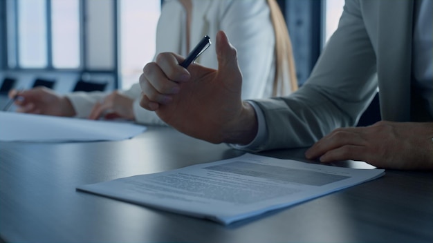 Closeup businessman hand holding pen reading contract agreement in office