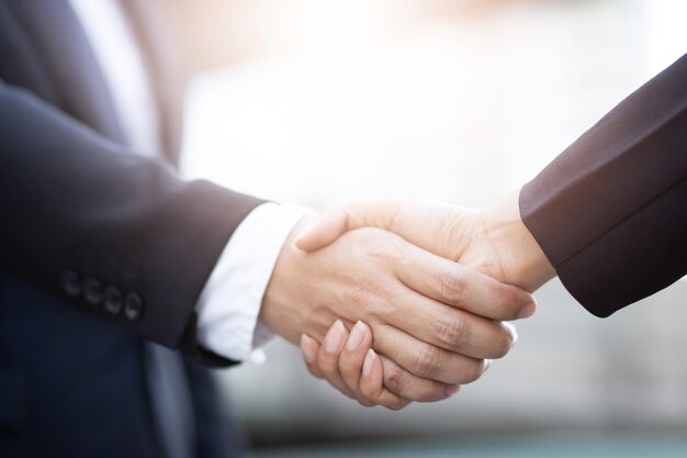 Photo closeup of a businessman hand shake businesswoman between two colleagues  ok, succeed in business holding hands.