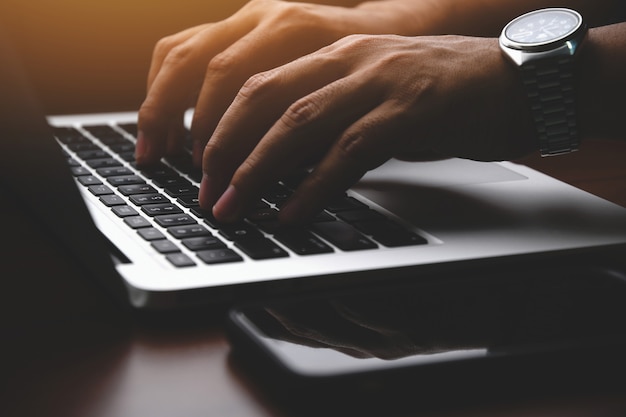 Closeup of a businessman hands working and typing on laptop keyboard