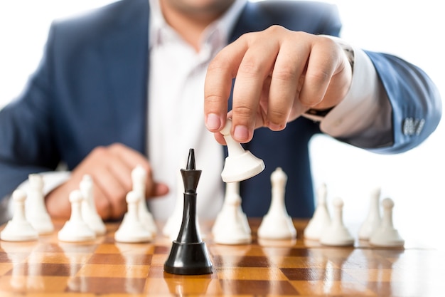 Closeup businessman playing chess and beating black king