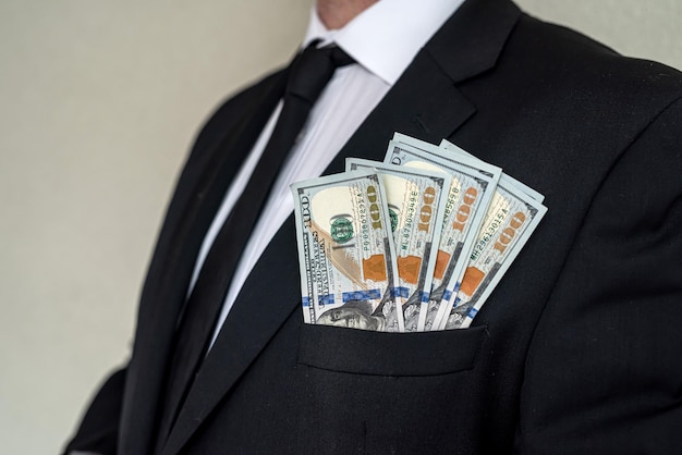 Closeup of businessman's hand in branded suit holding dollar banknotes