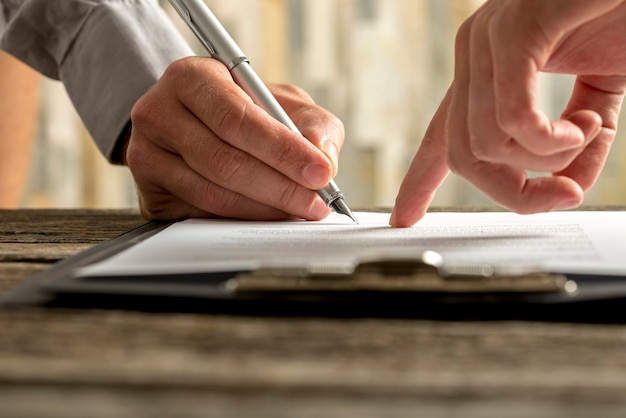 Photo closeup of businessman showing his new business partner where to sign an agreement