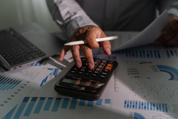 Близкий кадр бизнесмена, использующего ноутбук для анализа финансов и расчета инвестиционных данных, бумажной работы, отчета о деньгах, возмещения налогов, стоимости, бухгалтерского учета и банковской концепции.