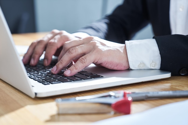 Uomo d'affari del primo piano che per mezzo del computer portatile per lavorare.