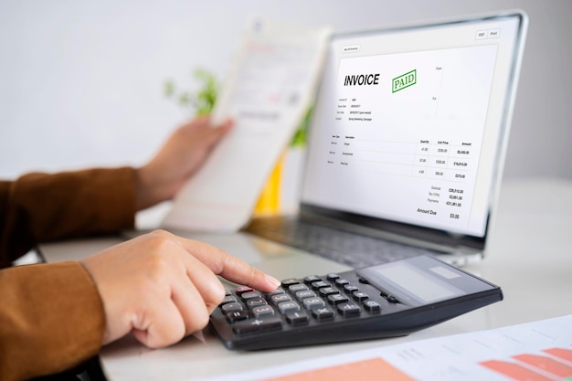 Photo closeup of a businessperson's hand calculating invoice at workplace