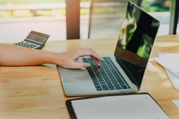 Foto primo piano delle mani della donna d'affari sul computer portatile alla scrivania dell'ufficio donna che utilizza il computer portatile per la ricerca sul web o la navigazione di informazioni sul concetto di ufficio a casa