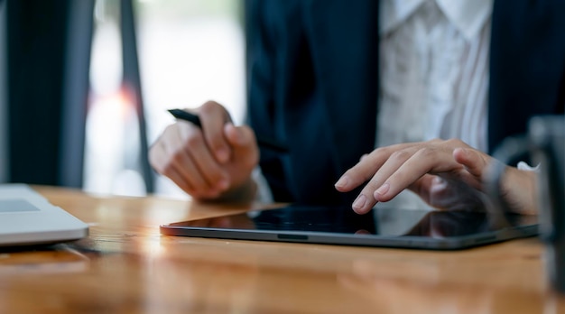 Closeup businesswoman hands using digital tablet sitting at her desk office