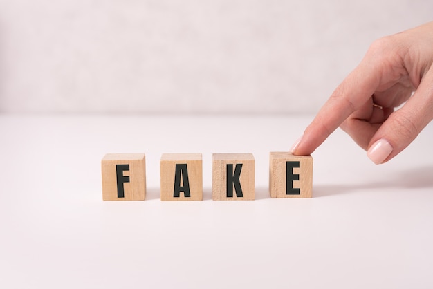 Closeup of businesswoman hold a cubes with word FAKE.