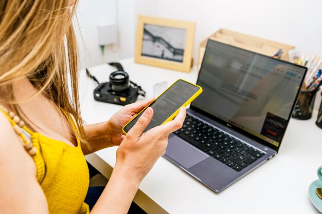 Closeup of Businesswoman with yellow shirt using phone from work at home