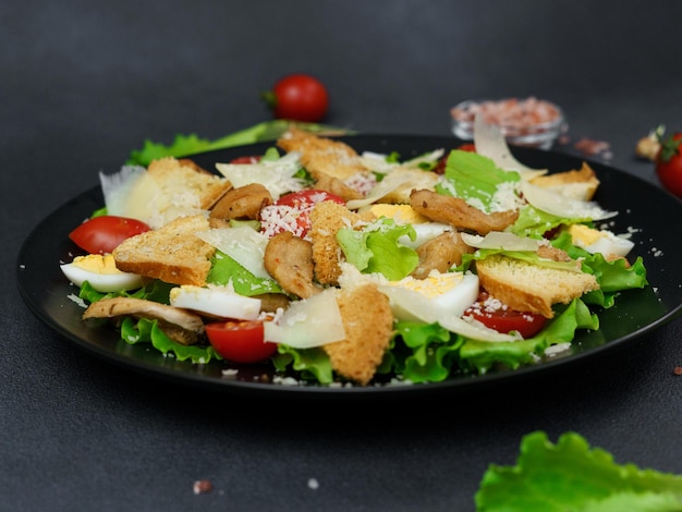 Closeup of a Caesar Salad in a black plate against a Black Background