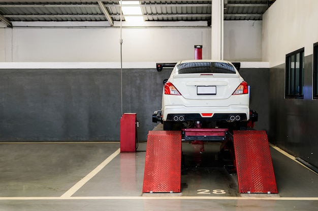 Automobile del primo piano nel centro di servizio di riparazione dell'automobile con il fuoco molle e sopra luce nei precedenti